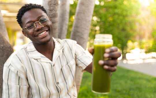 man drinking a green cleanse drink