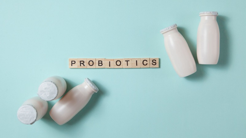 Milk glasses around Probiotics spelled out in wooden letters