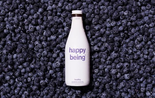 Blueberries underneath a bottle of happy being tea