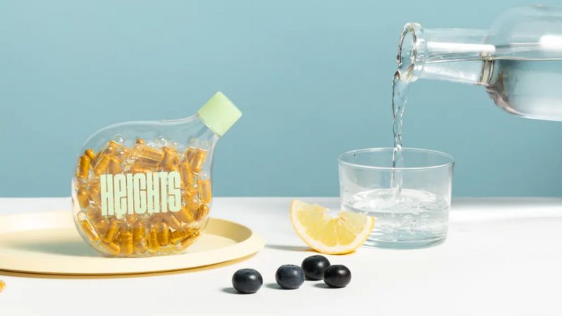 Pouring glass of water next to heights smart vitamins
