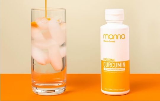 Liquid curcumin added to a glass of water next to manna liposomal curcumin